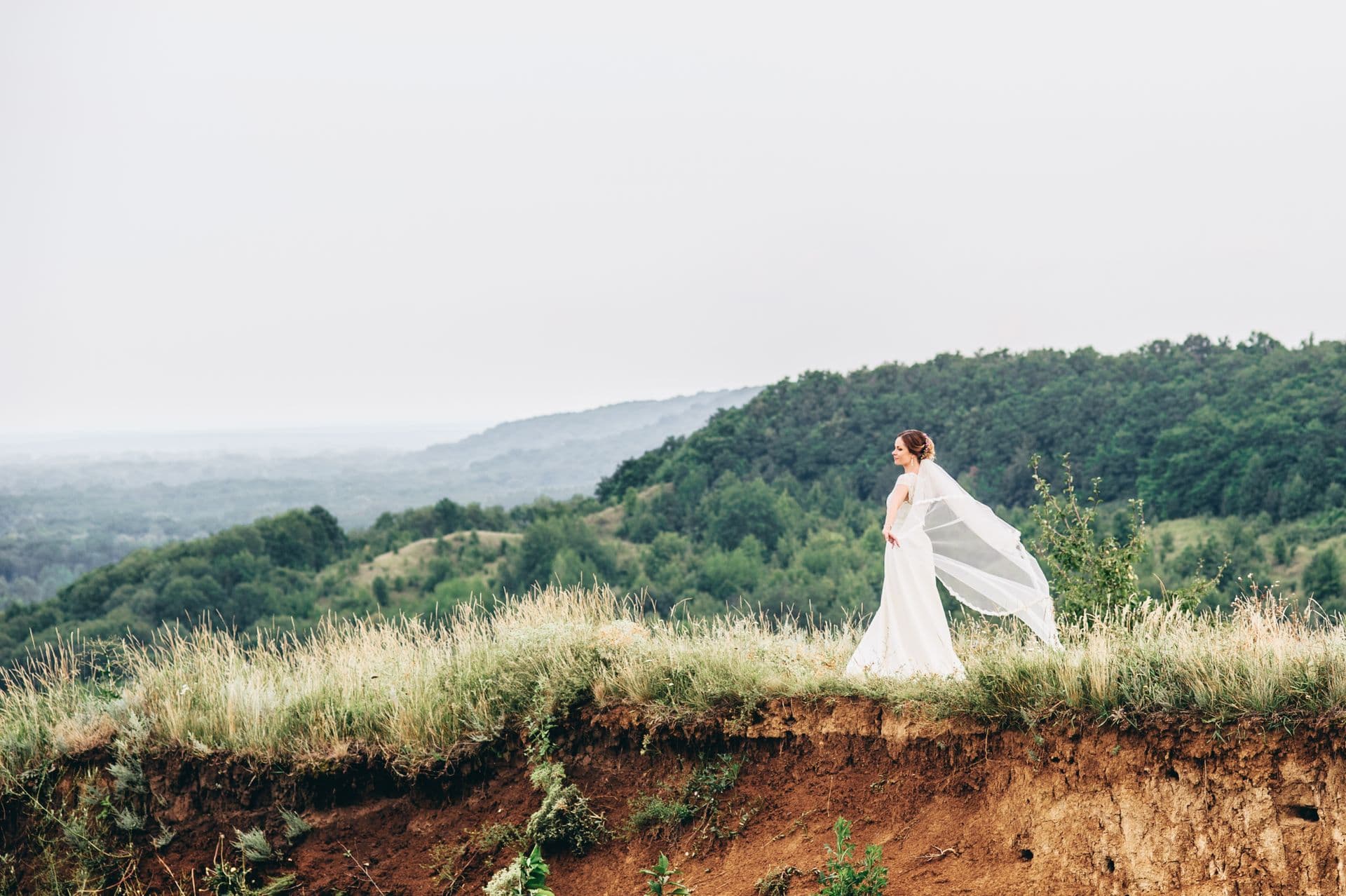 Bride with a flowing veil against a coastal landscape